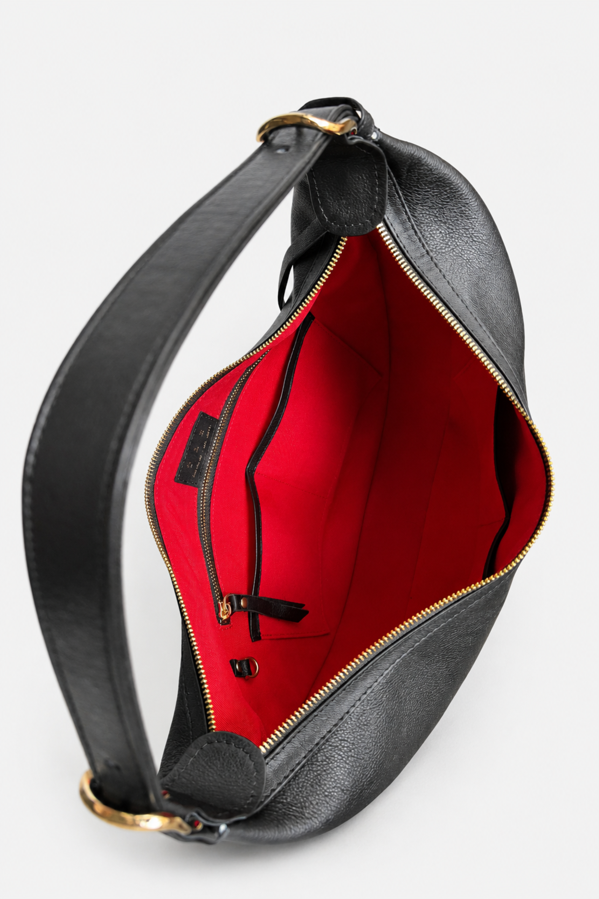 Black leather shoulder bag with a red interior lining and gold-tone hardware, shown open, with compartments visible 