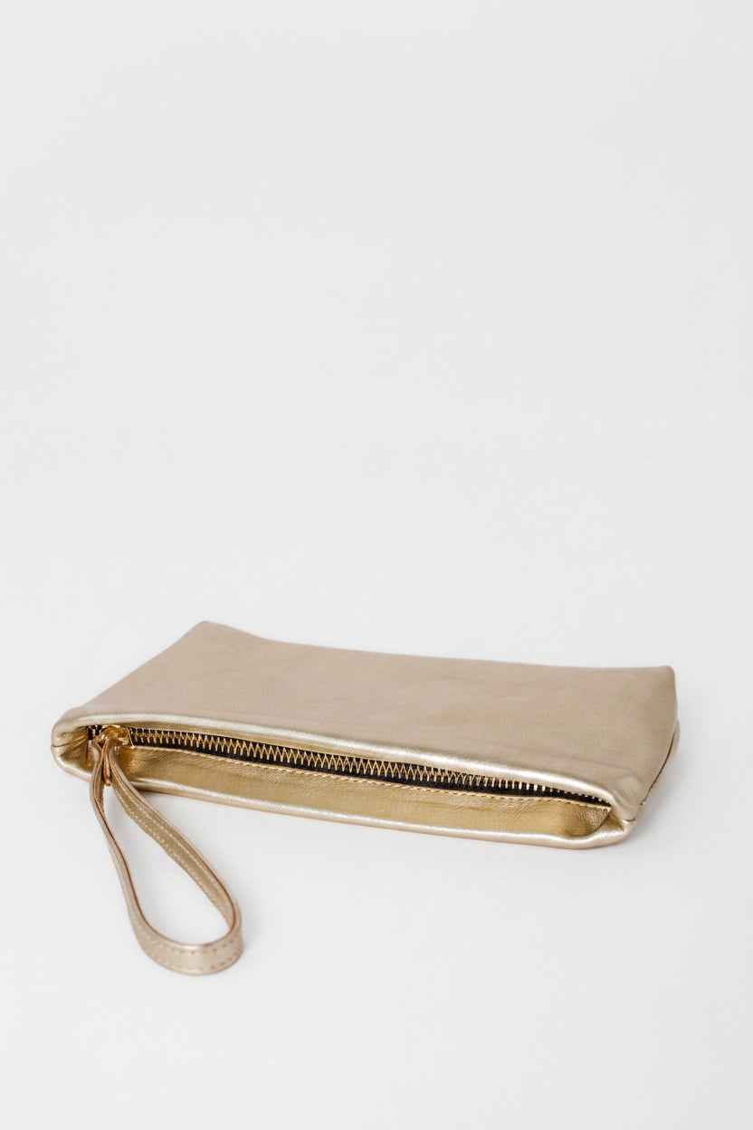 Bella compact wristlet in metallic gold with a wristlet and zipper closure. The clutch is showing the side view
