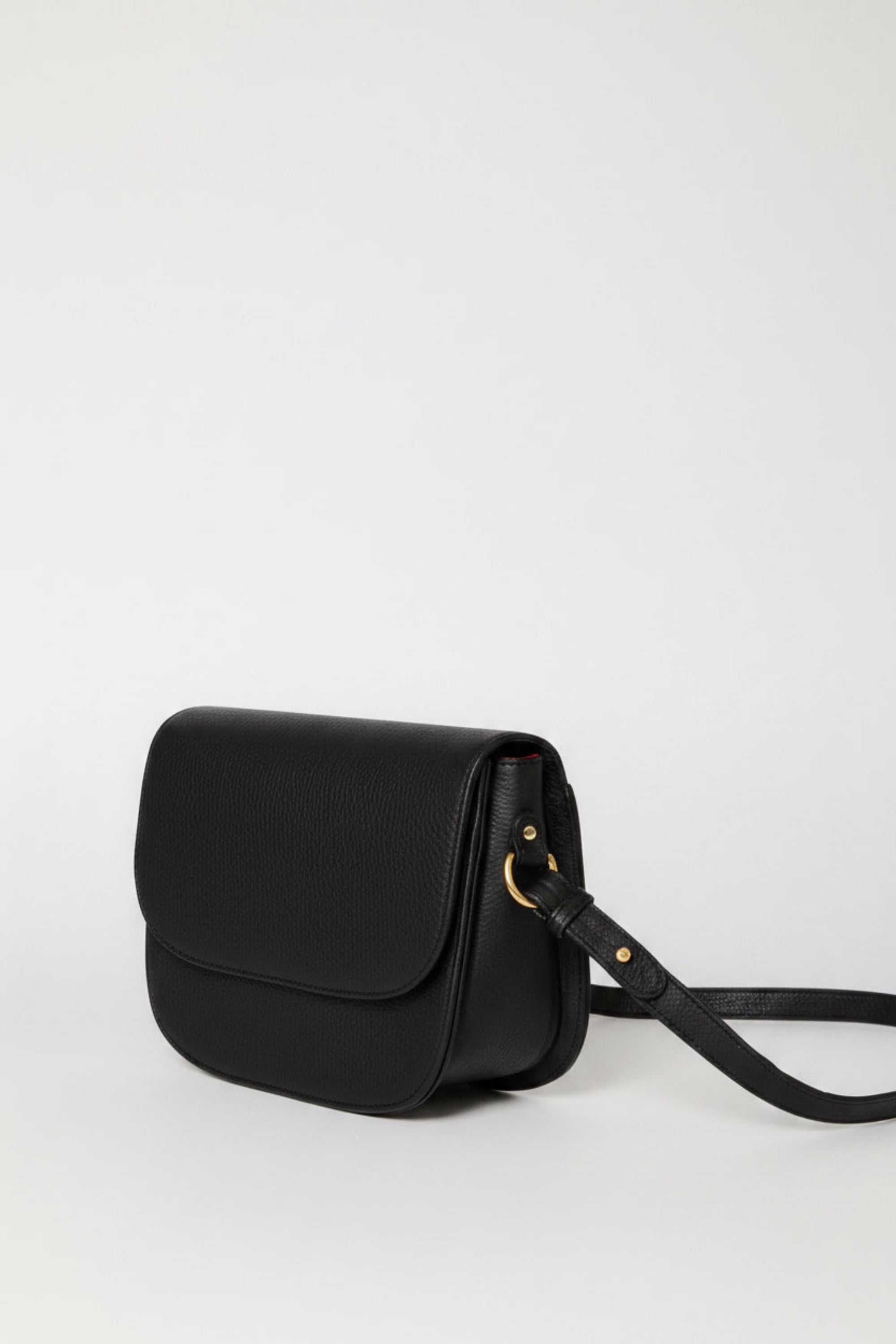 Handcrafted leather saddle bag with shoulder strap and gold hardware. Simple, clean design, shown from the side view