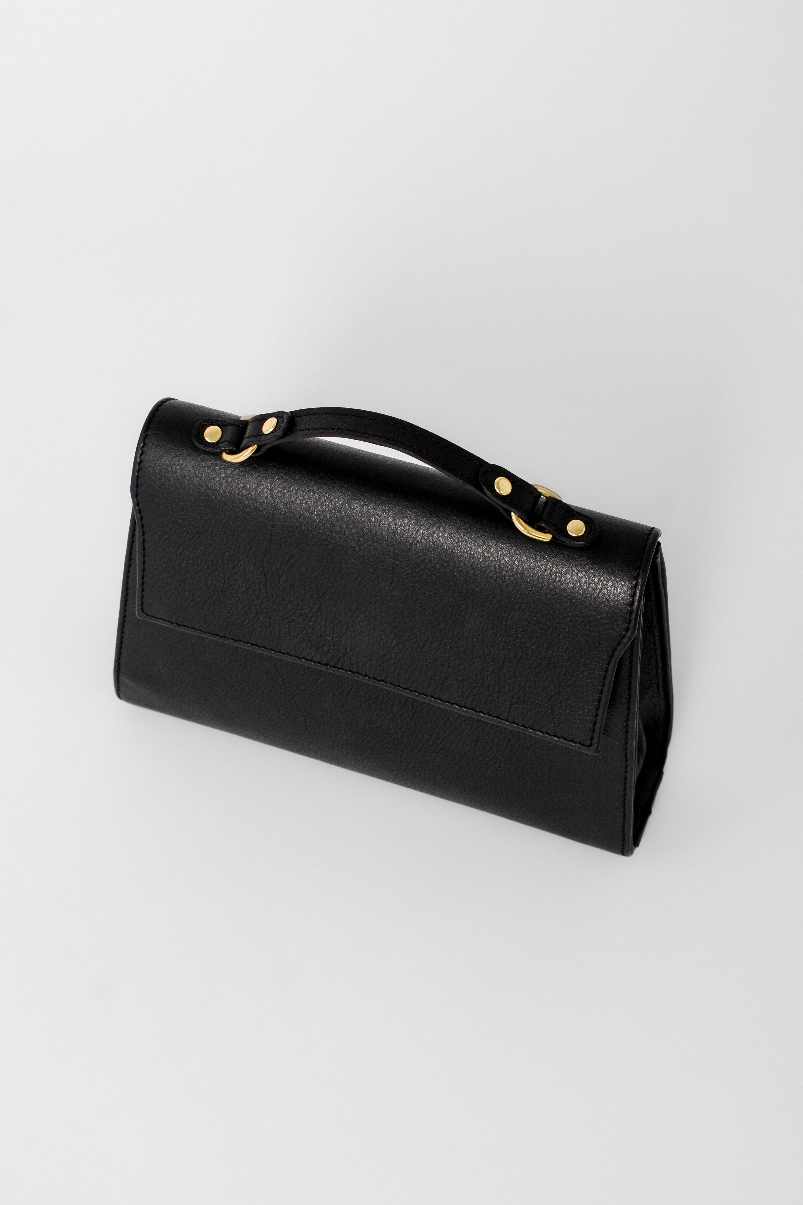 Back view of the black leather Carrie Petite top-handle bag, showcasing its clean, minimal design and structured silhouette for refined everyday or evening use.
