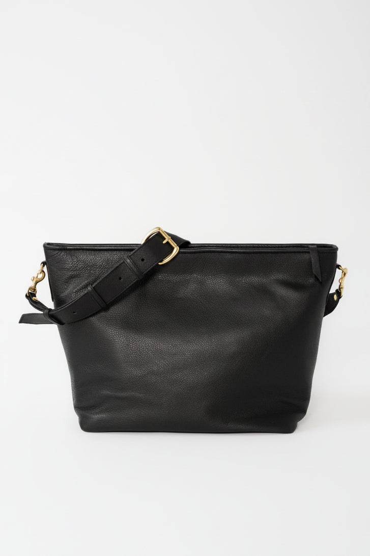 A black leather shoulder bag with a wide top opening, a matching adjustable shoulder strap with gold-tone hardware, and gold-tone side D-ring.