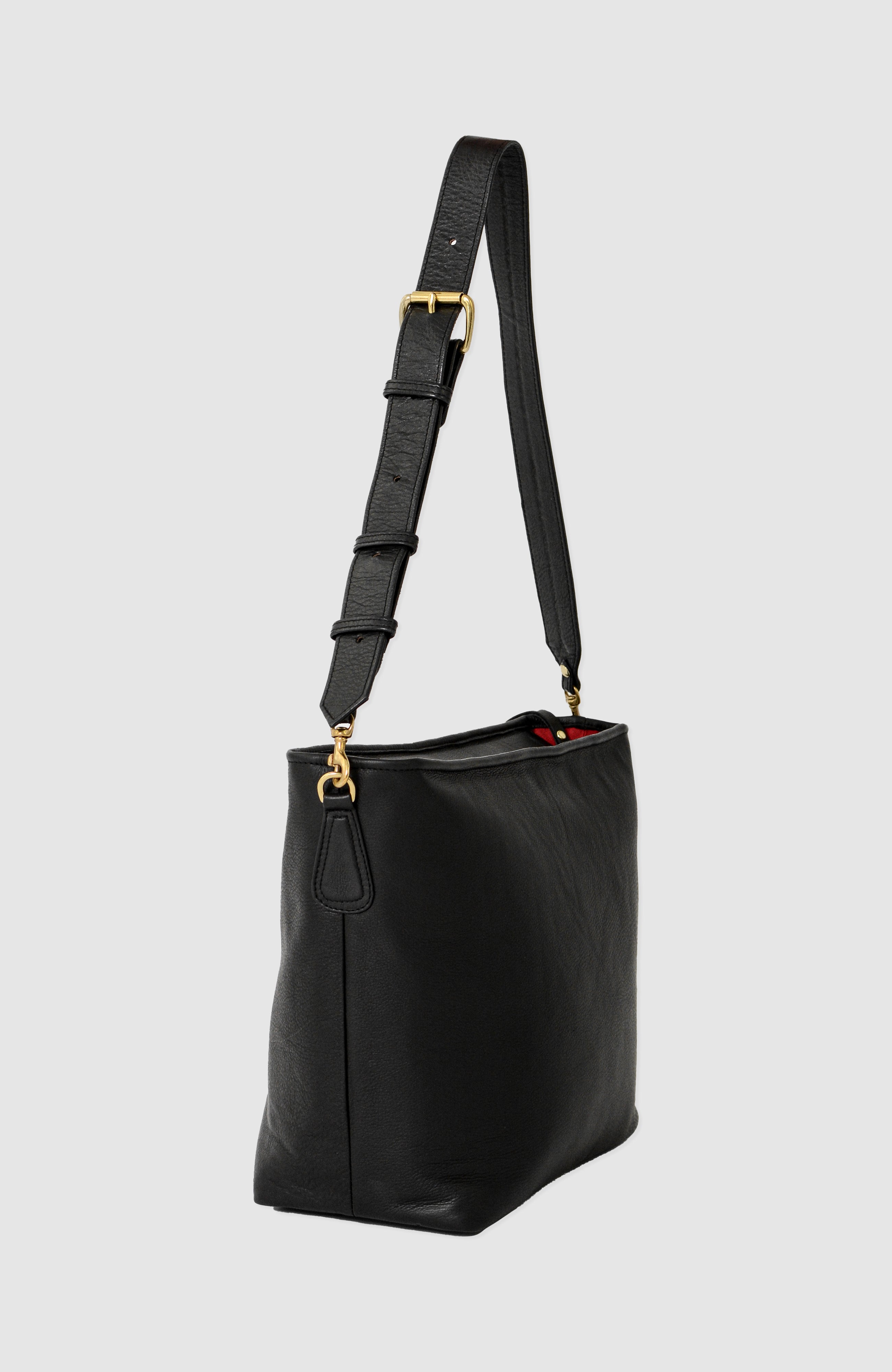 Charlee Petite in full-grain leather with brass hardware, compact slouchy silhouette, exterior phone pocket, interior compartments, and adjustable shoulder strap.