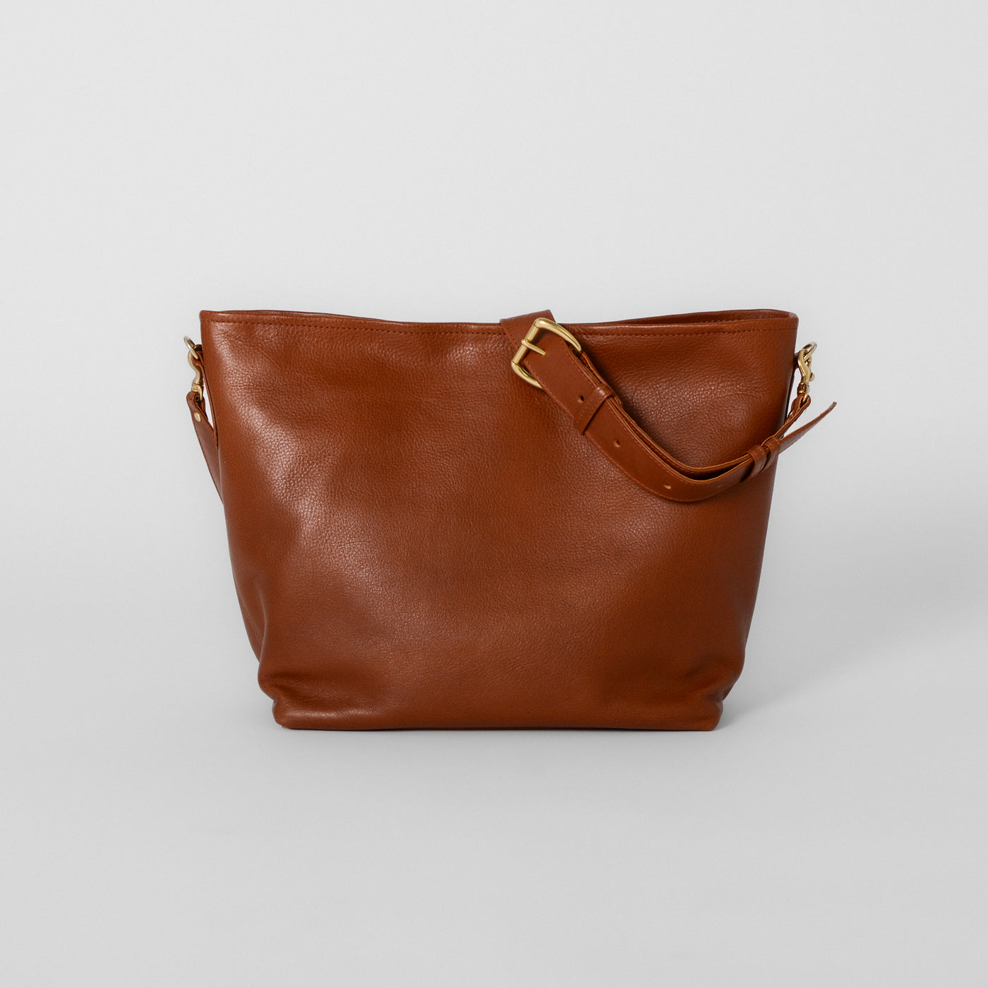 The Charee Slouchy Tote in the color brown with a shoulder strap and gold hardware details.