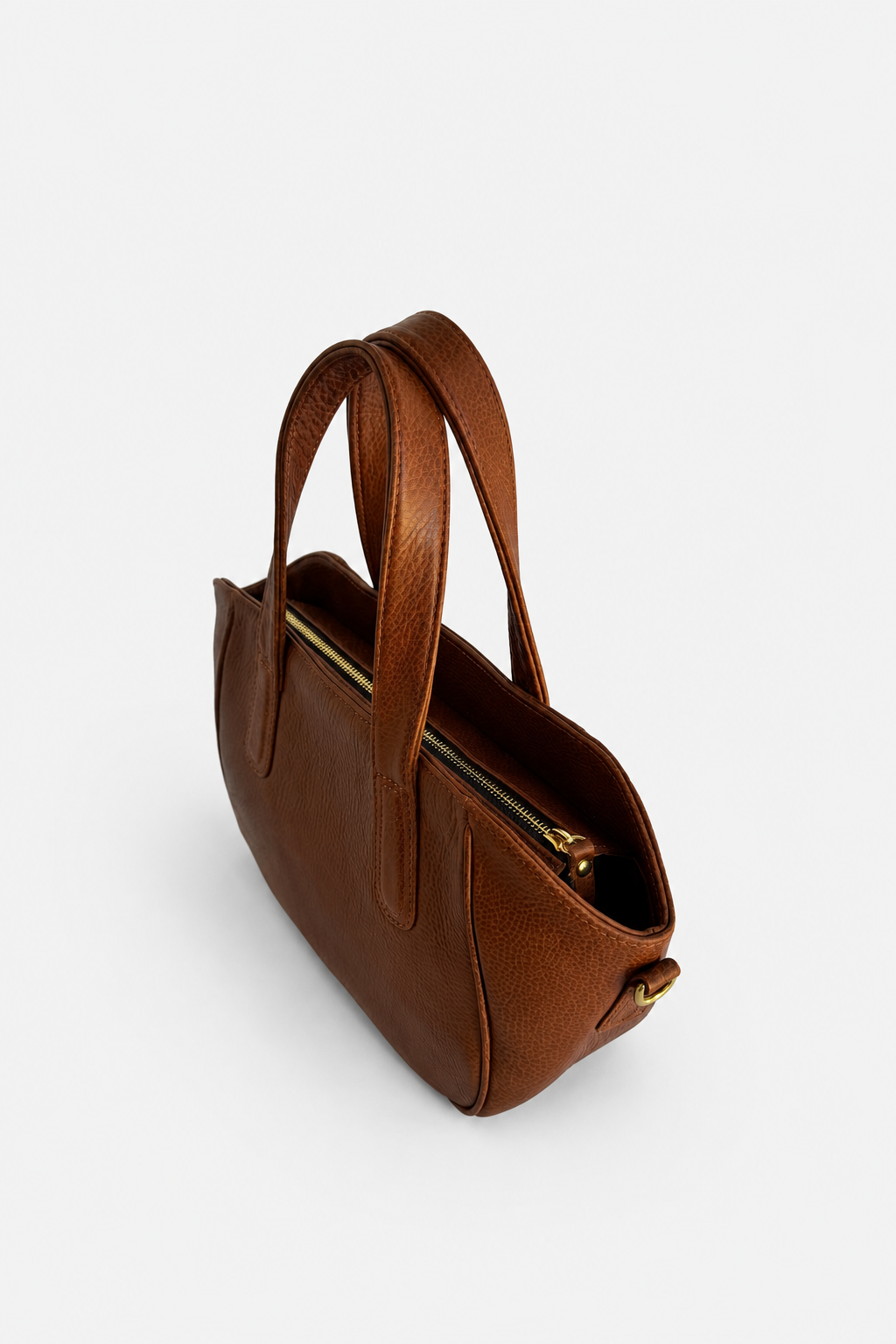 A brown leather handbag with double top handles and a gold zipper, shown from an elevated angle on a light gray background.