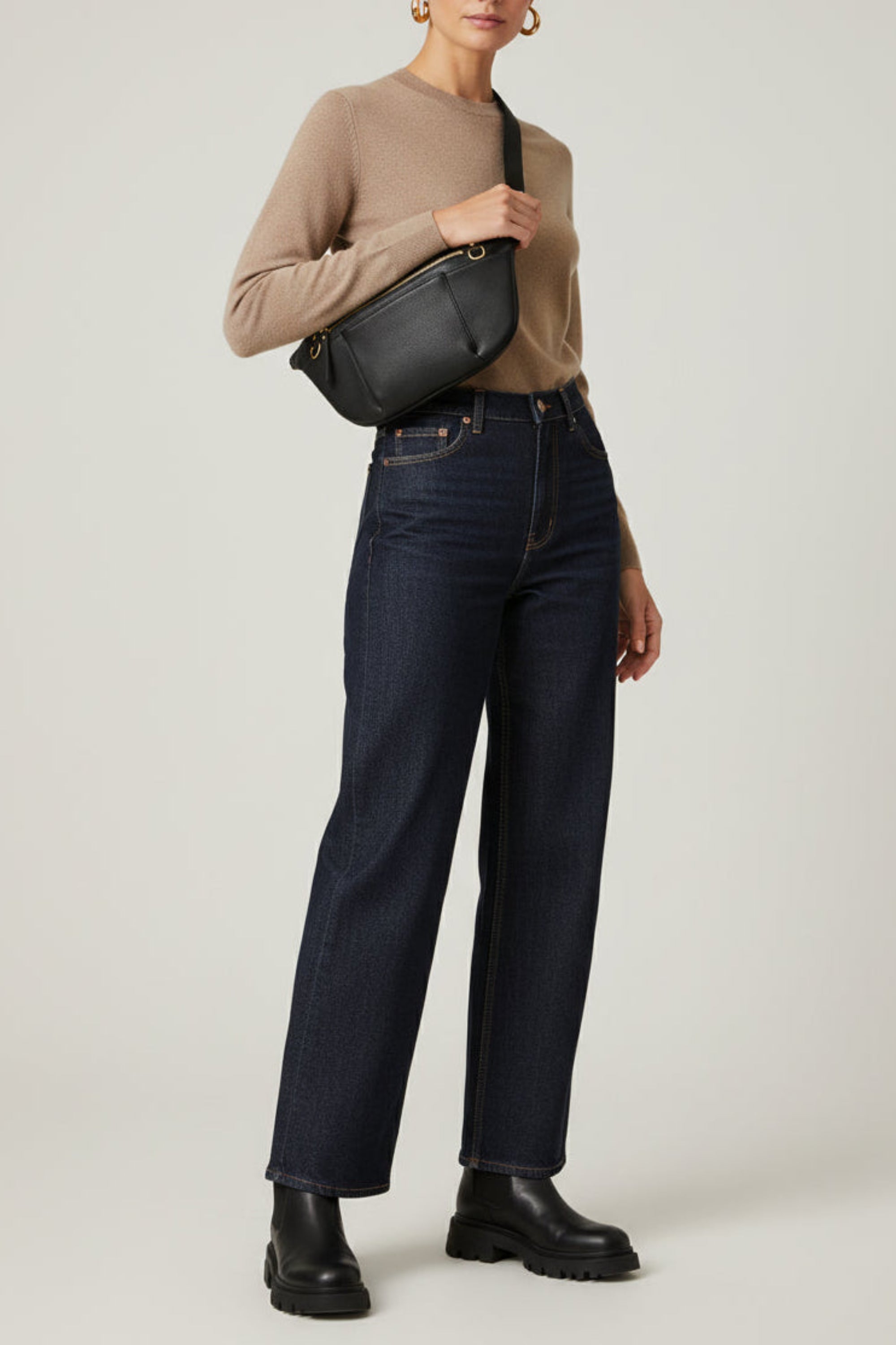 Black leather commuter sling bag worn crossbody, featuring an adjustable strap, zip compartments, and gold hardware, styled as a hands-free everyday bag for work, travel, and daily use.