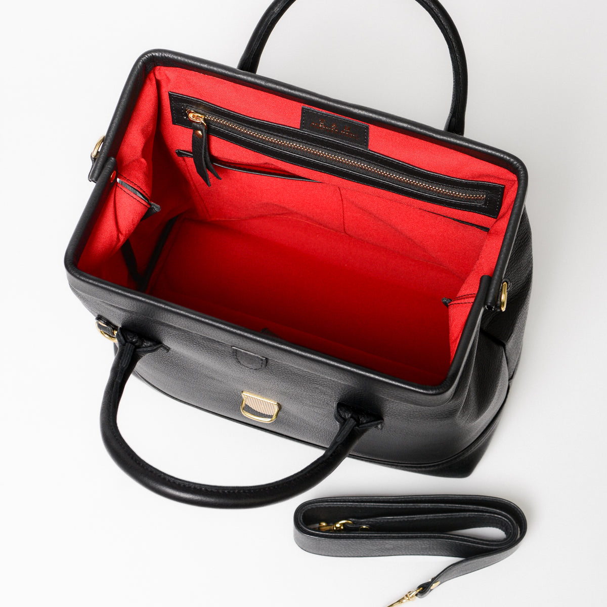 A black leather doctor bag with a metal frame with red lining and a gold zipper pocket. 
