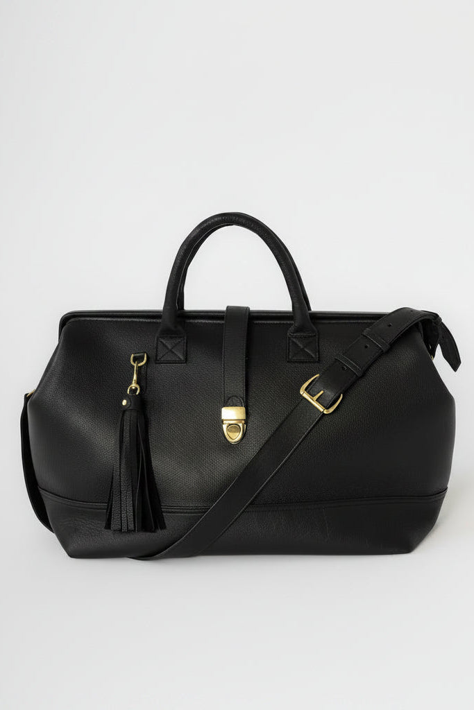 Black leather bag with gold hardware and tassel on a white background