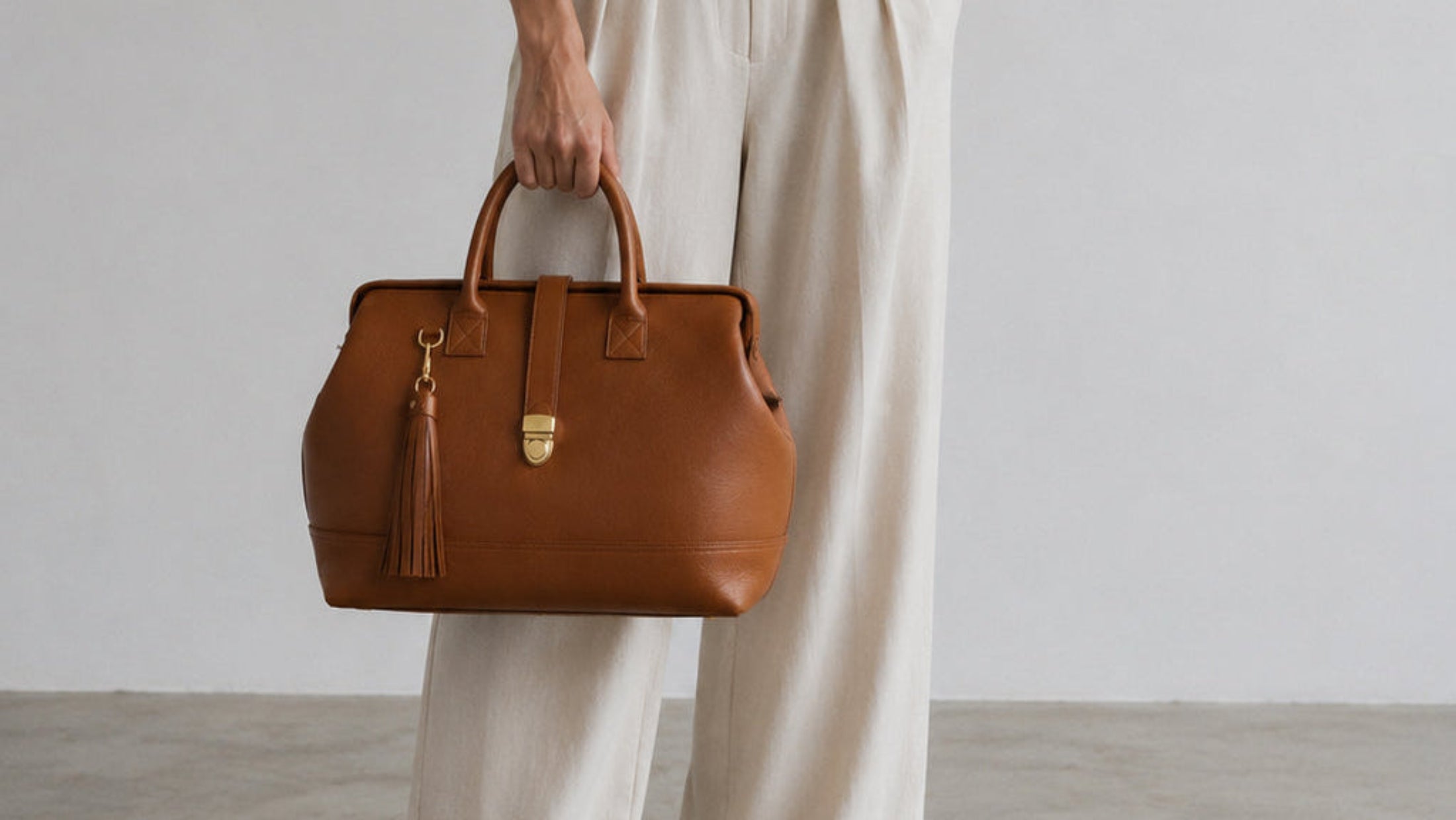 Handcrafted leather Doctor Bag in the color brown with a metal frame closure and gold hardware details. 