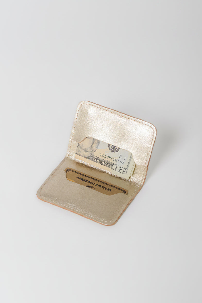 Folder over wallet, metallic gold leather interior view showing cash and a credit card inside 