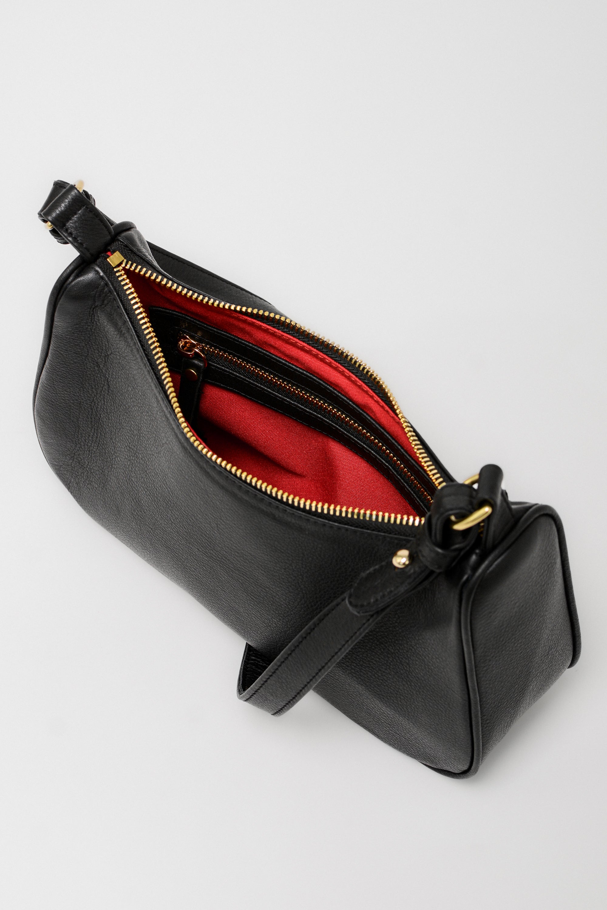 Black handbag with red interior on a light gray background