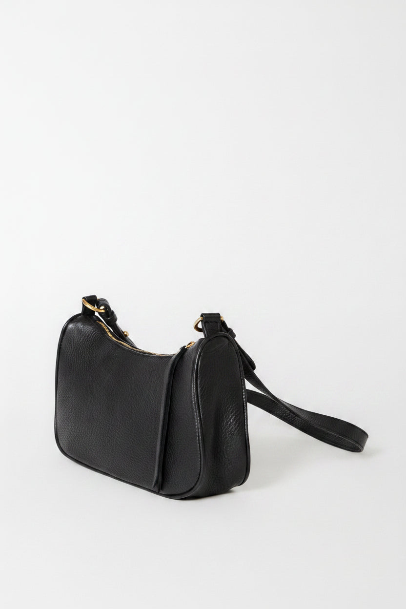 A black leather shoulder bag with a curved top and a long strap, photographed on a clean white background.