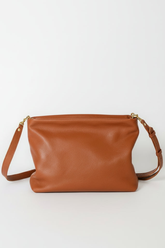 Brown leather soft handbag with a strap on a white background