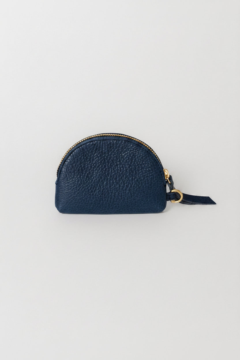 A leather half moon coin purse in the color blue with a white background. 