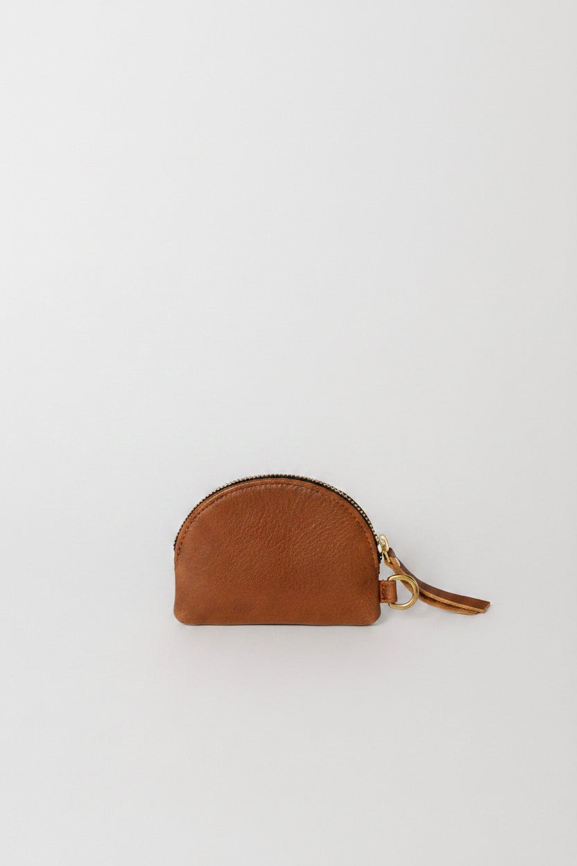 A small semi-circular brown leather pouch with a gold zipper and a matching leather tassel pull, photographed on a clean white background.
