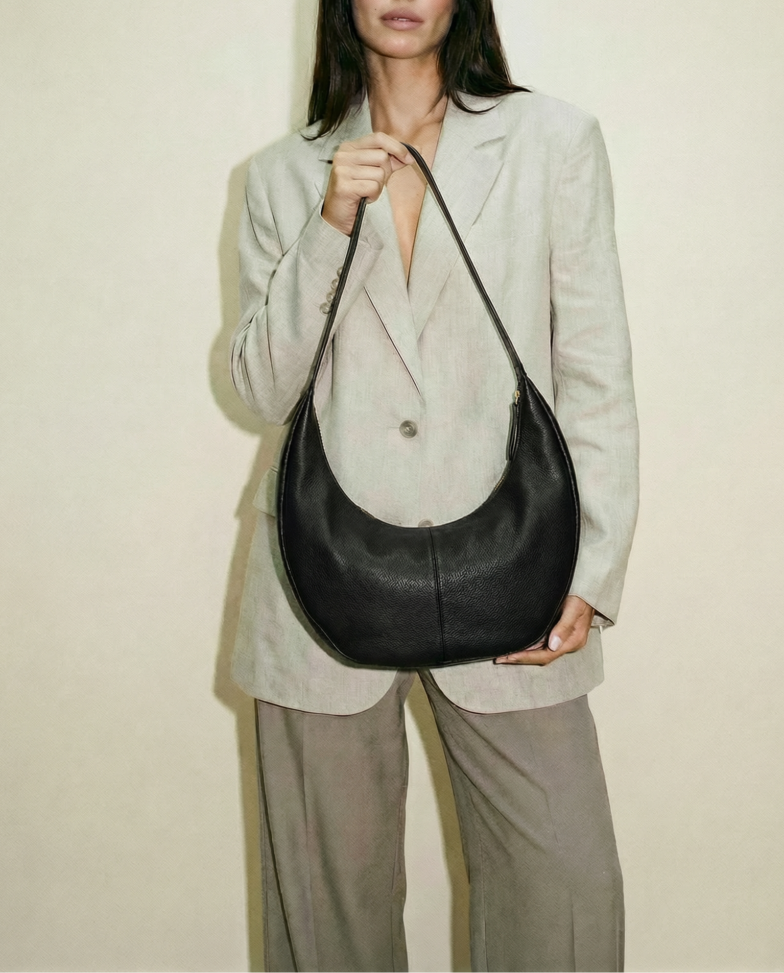 Woman holding a black leather handbag against a plain background