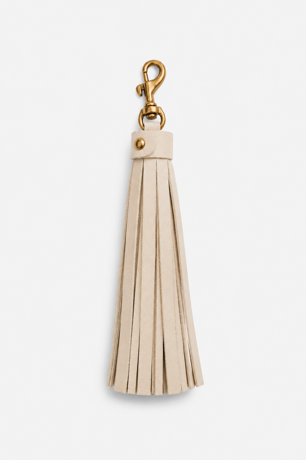 An ivory leather tassel keychain with a gold-tone metal lobster clasp and rivet, shown against a plain light gray background.