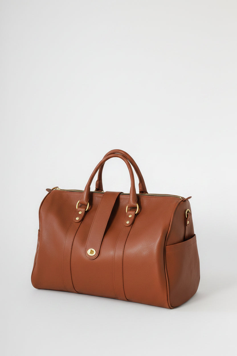 Loen Weekender Duffle in brown leather with two handles, and solid brass hardware from the side view.
