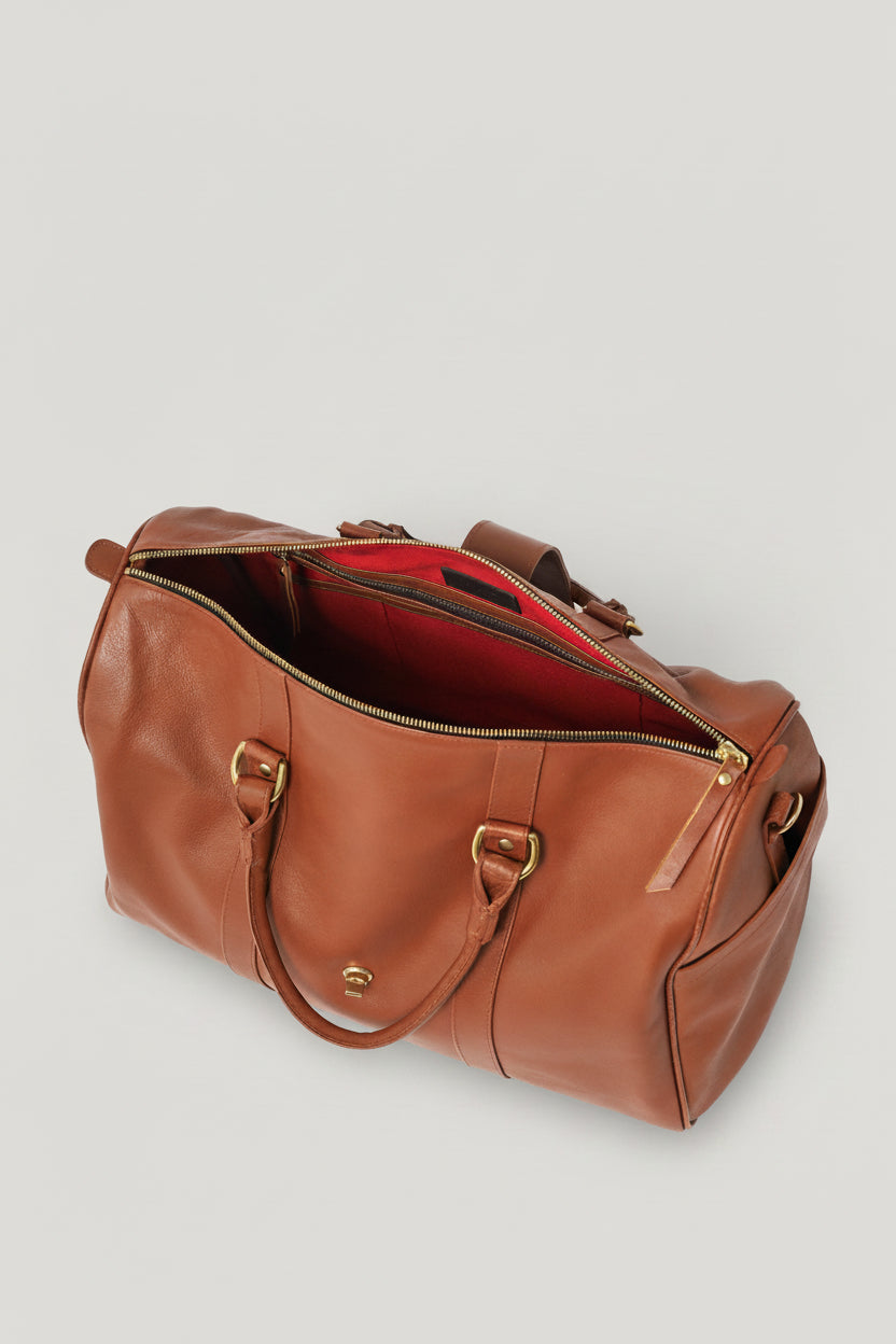 Loen Weekender Duffle in Brown Leather showing the red Interior from the top view amd the zipper closure. 