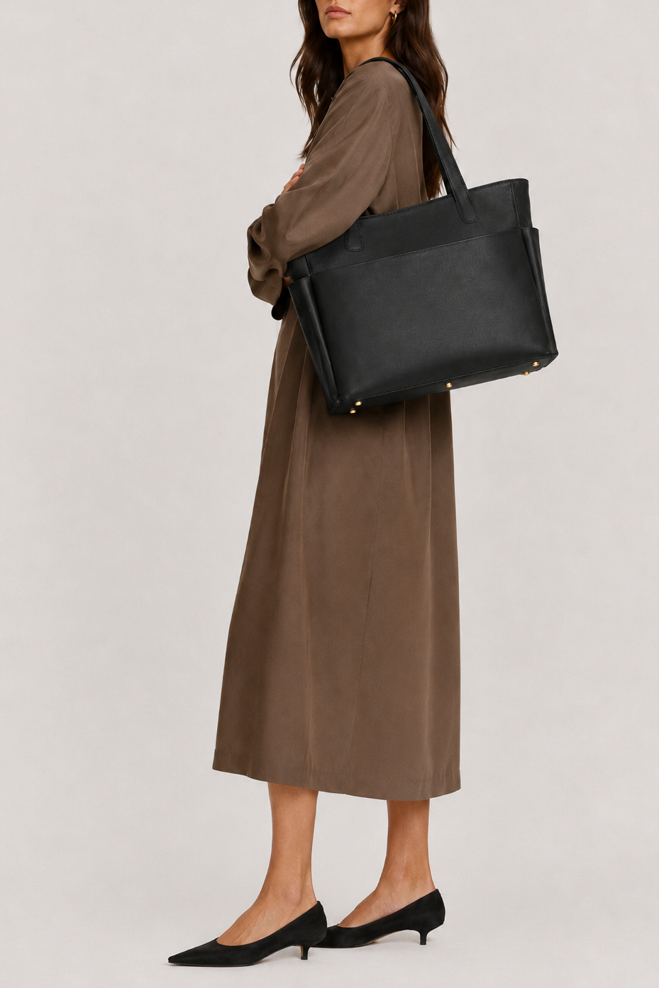 Model carrying the TAH Mari Oversized Structured Tote in black full-grain leather with solid brass feet, styled with a silk maxi dress and black kitten heels.