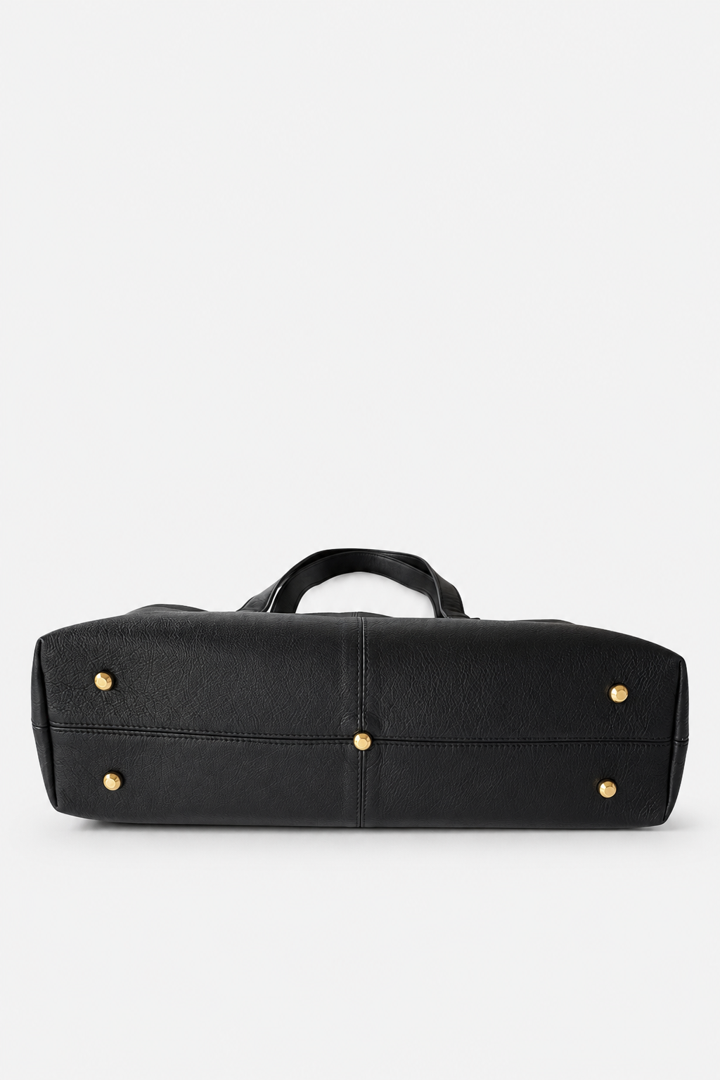The bottom of a black leather tote bag featuring the soild brass feet. This bag is the Megan Everyday Tote bag. 