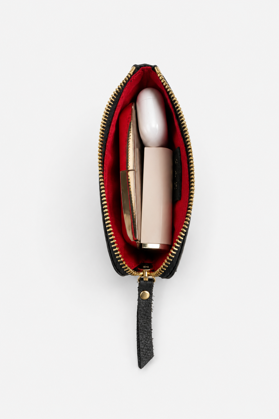 An open black leather zip pouch with a red interior lining and gold-tone zipper, shown against a plain white background. Inside are two cosmetic items: AirPods and a pale pink cylindrical tube lipstick with a gold cap and a cosmetic case. 