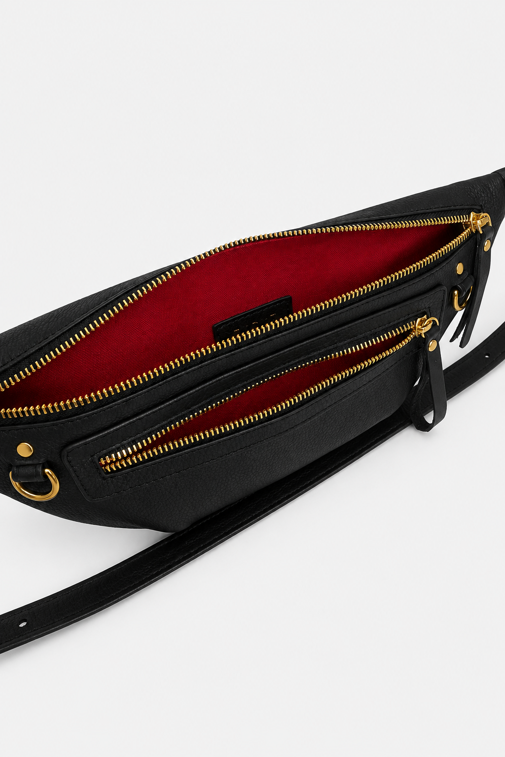 Nomad Fanny Pack in black full-grain leather open from above, revealing vibrant red interior lining, gold zipper pulls, interior zip pocket, D-ring, and multiple compartments for organized everyday storage.