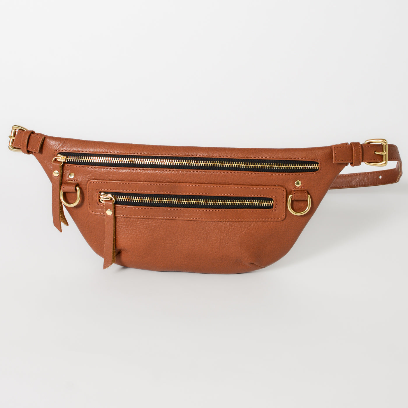 Cognac leather fanny pack belt bag with adjustable strap, multiple zip pockets, and gold hardware, designed as a hands-free everyday bag for travel, errands, and daily essentials.