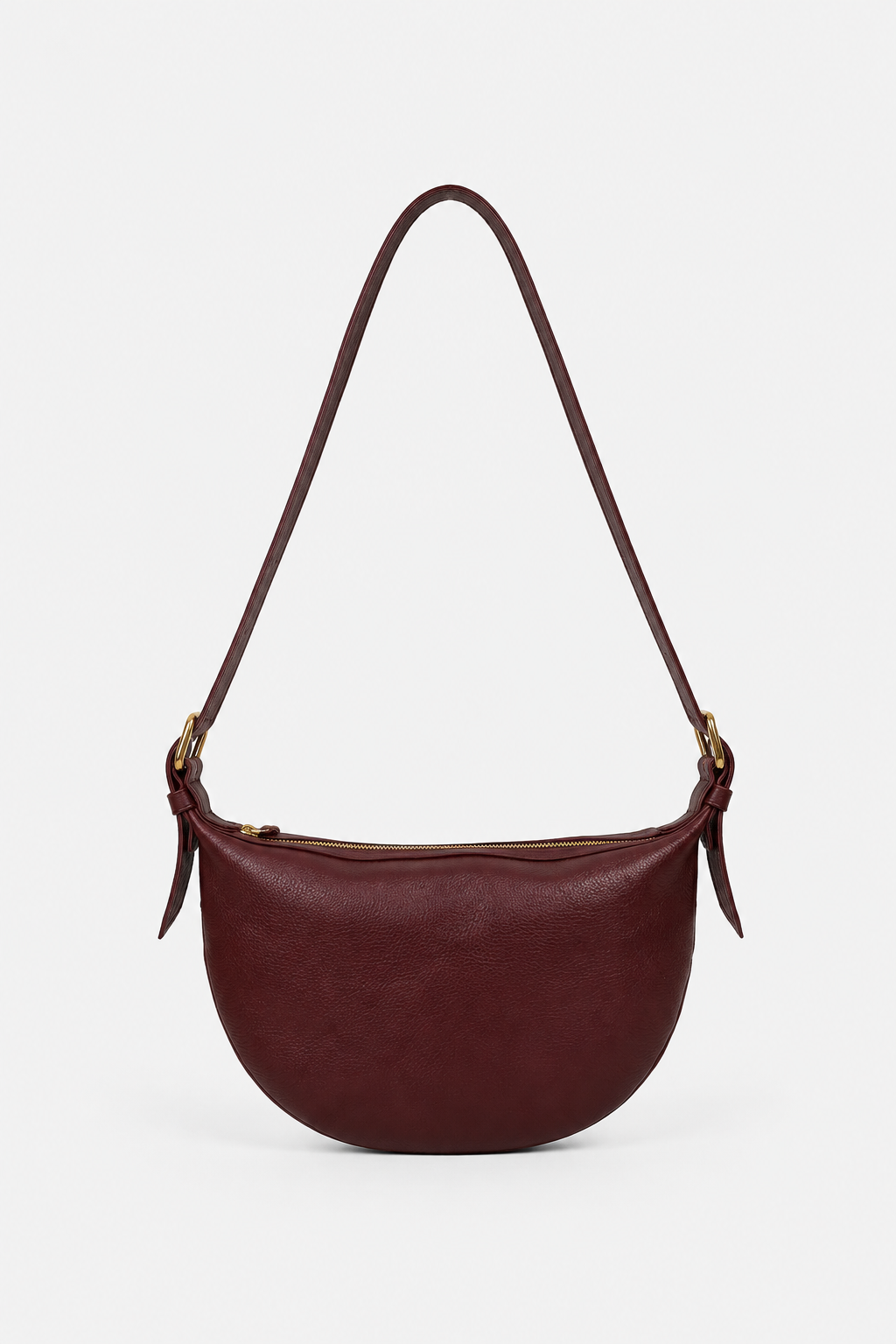A dark burgundy leather crescent-shaped shoulder bag with a single adjustable strap and gold-tone hardware. Wear as a crossbody or over the shoulder.
