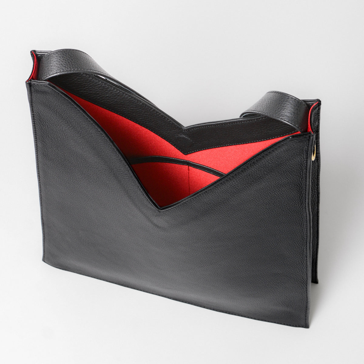 A black vie shaped tote bag in black leather showing the red interior.