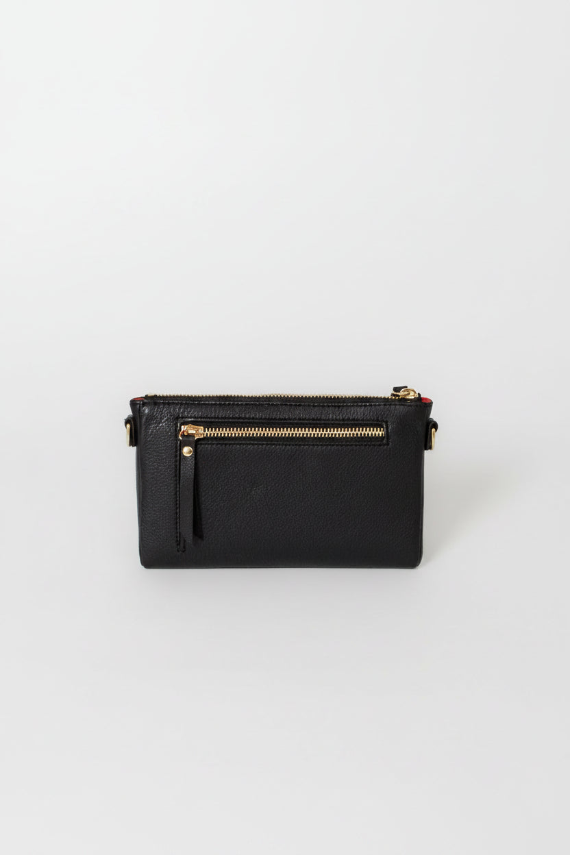 A black leather crossbody clutch bag with gold-tone hardware, featuring a top zipper, a front zip pocket with a tassel pull, and a small side strap, shown on a light gray background.