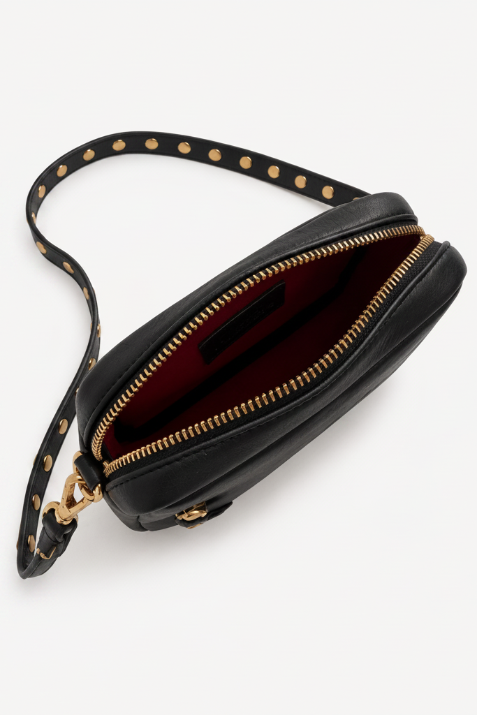 Interior view of the black leather Ami Crossbody bag featuring a red lining, zip-top closure, and compact compartment for essentials.