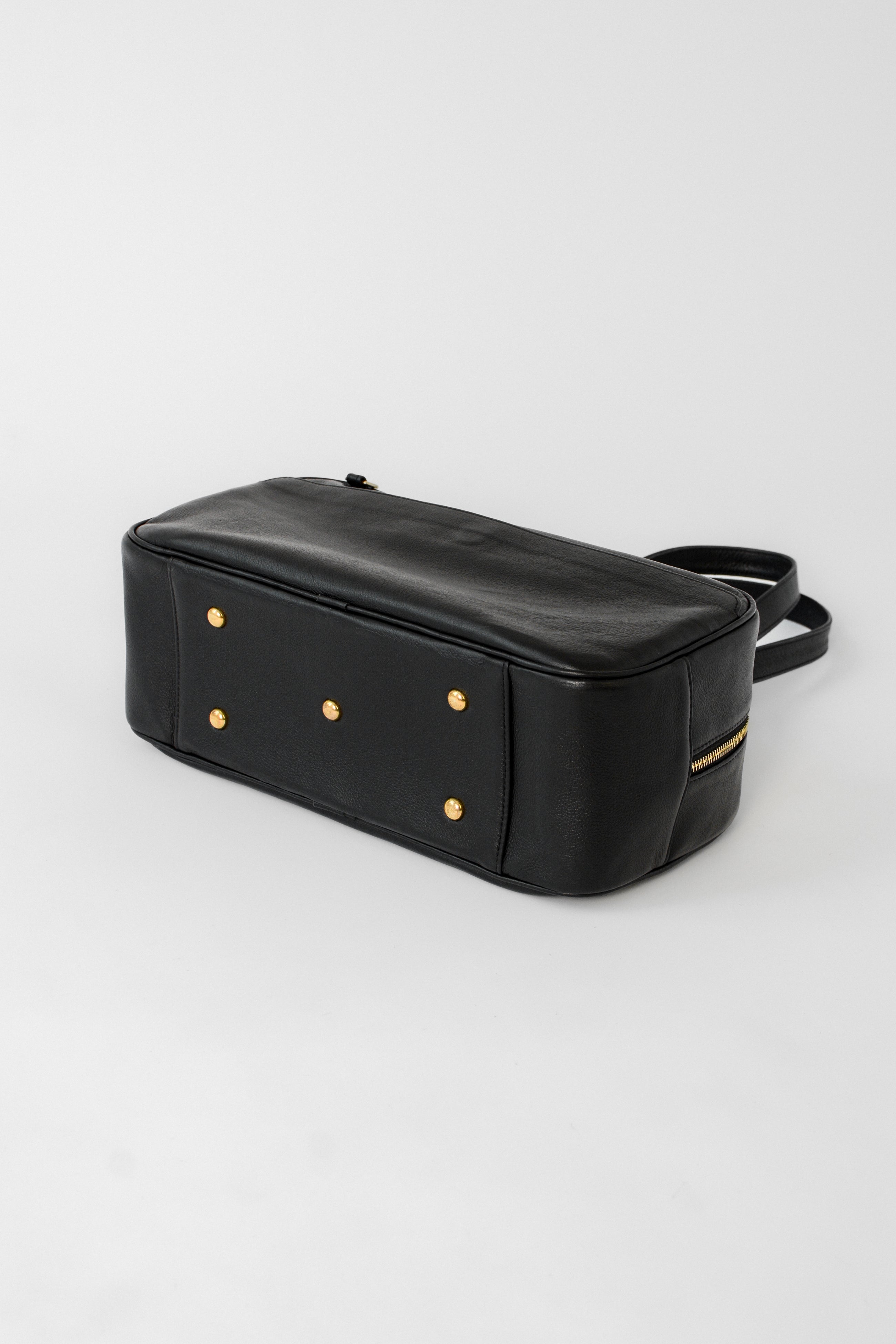 Bottom view of the black leather Ari Bowler Bag featuring solid brass feet for protection, structured base, and durable everyday design.