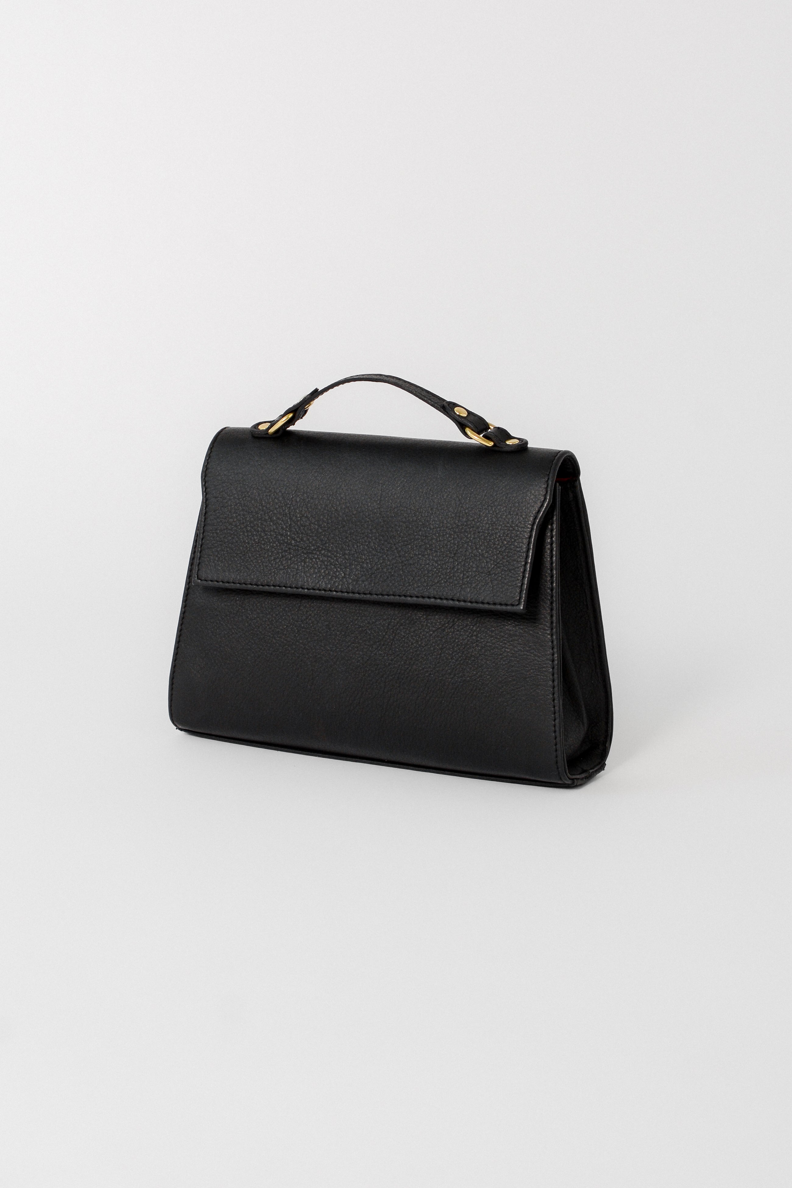 Black leather Carrie Petite top-handle bag designed for evening and occasion wear, featuring a structured silhouette, flap closure, and refined gold hardware.