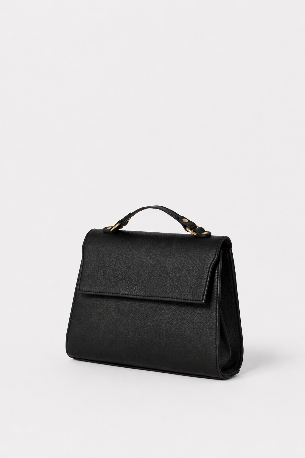 Black leather Carrie Petite top-handle bag with structured silhouette and flap closure, featuring gold hardware and a refined, minimalist design.