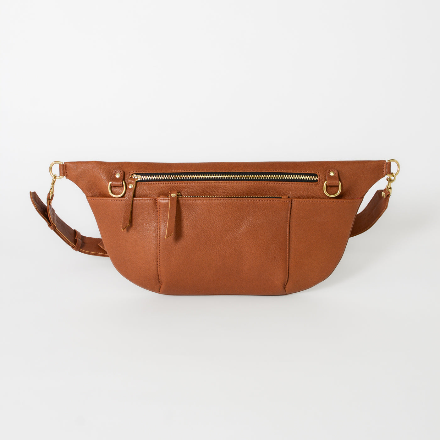 Cognac leather commuter sling bag with adjustable strap, zip compartments, and gold hardware, designed as a hands-free crossbody bag for work, travel, and everyday essentials.