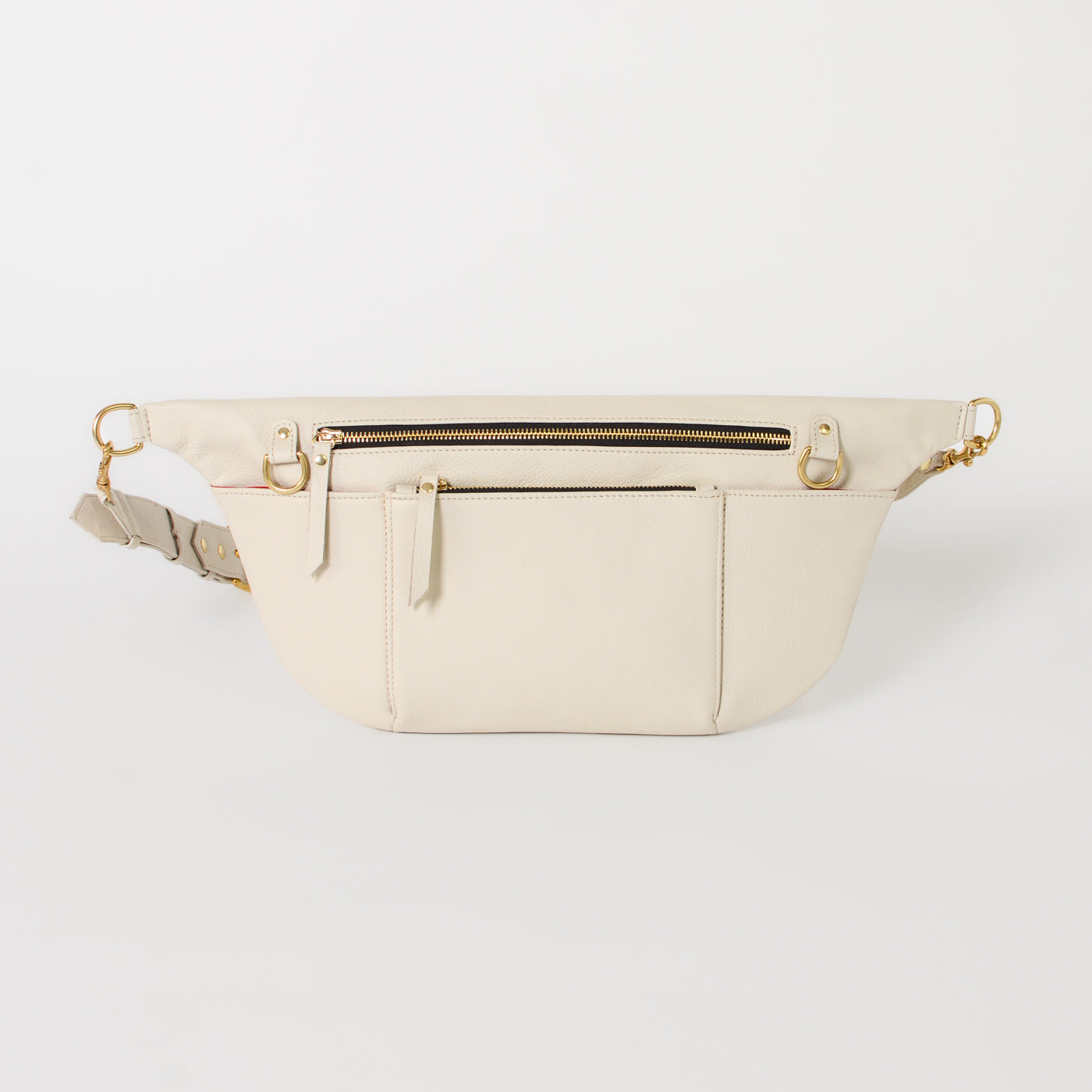 Ivory leather commuter sling bag with adjustable strap, zip compartments, and gold hardware, designed as a refined, hands-free crossbody bag for work, travel, and everyday essentials.