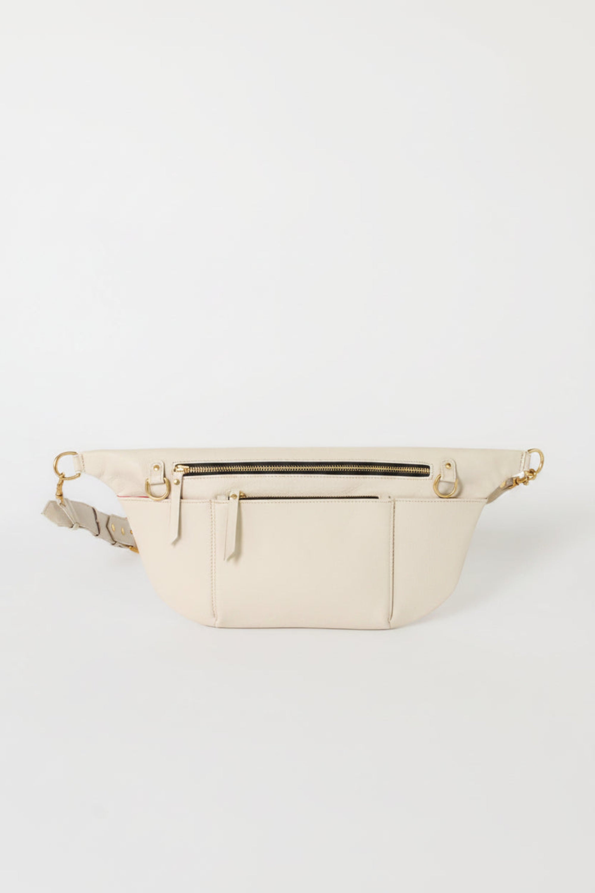 Ivory leather commuter sling bag with adjustable strap, zip compartments, and gold hardware, designed as a refined, hands-free crossbody bag for work, travel, and everyday essentials.