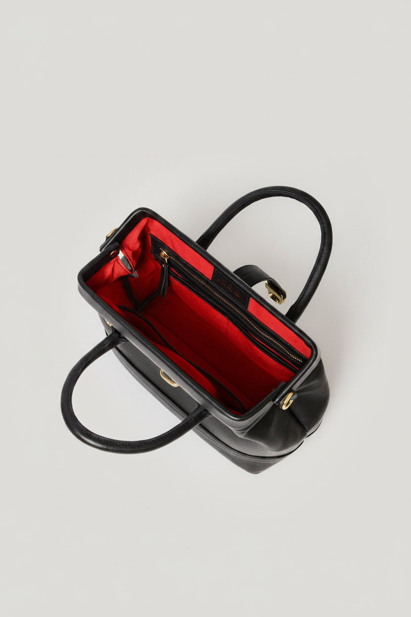 Top-down view of the Doctor Bag interior, featuring a structured frame opening, red lining, a zip pocket, and organized compartments.