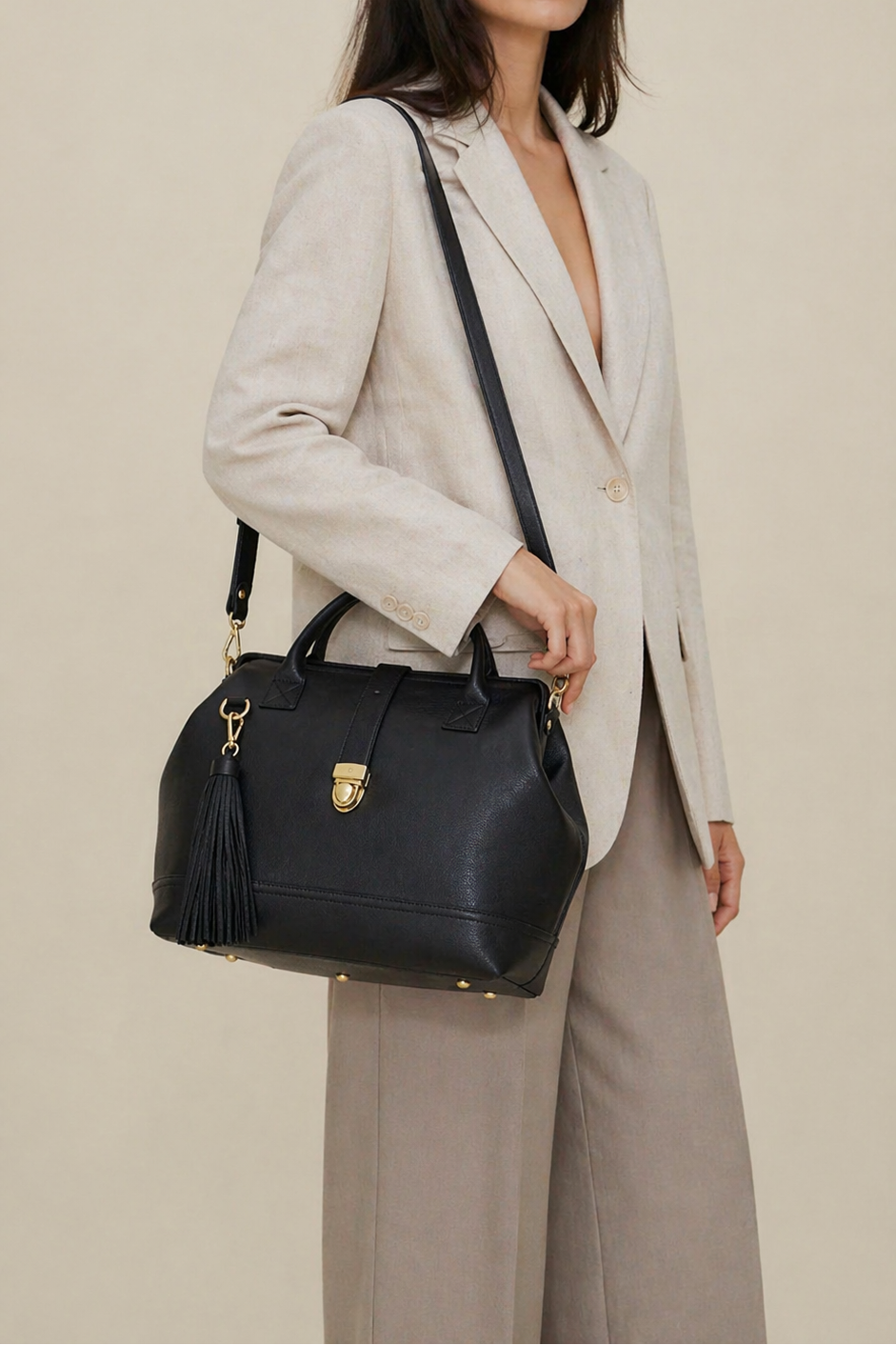 Woman wearing the Doctor Bag in black leather with detachable shoulder strap and tassel detail, styled with a relaxed tailored look.