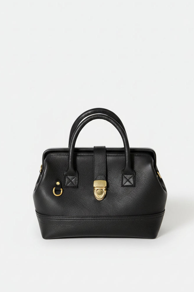 Front-facing hero image of the Doctor Bag Petite in black leather, featuring structured top handles, a framed silhouette, and a polished gold clasp closure.