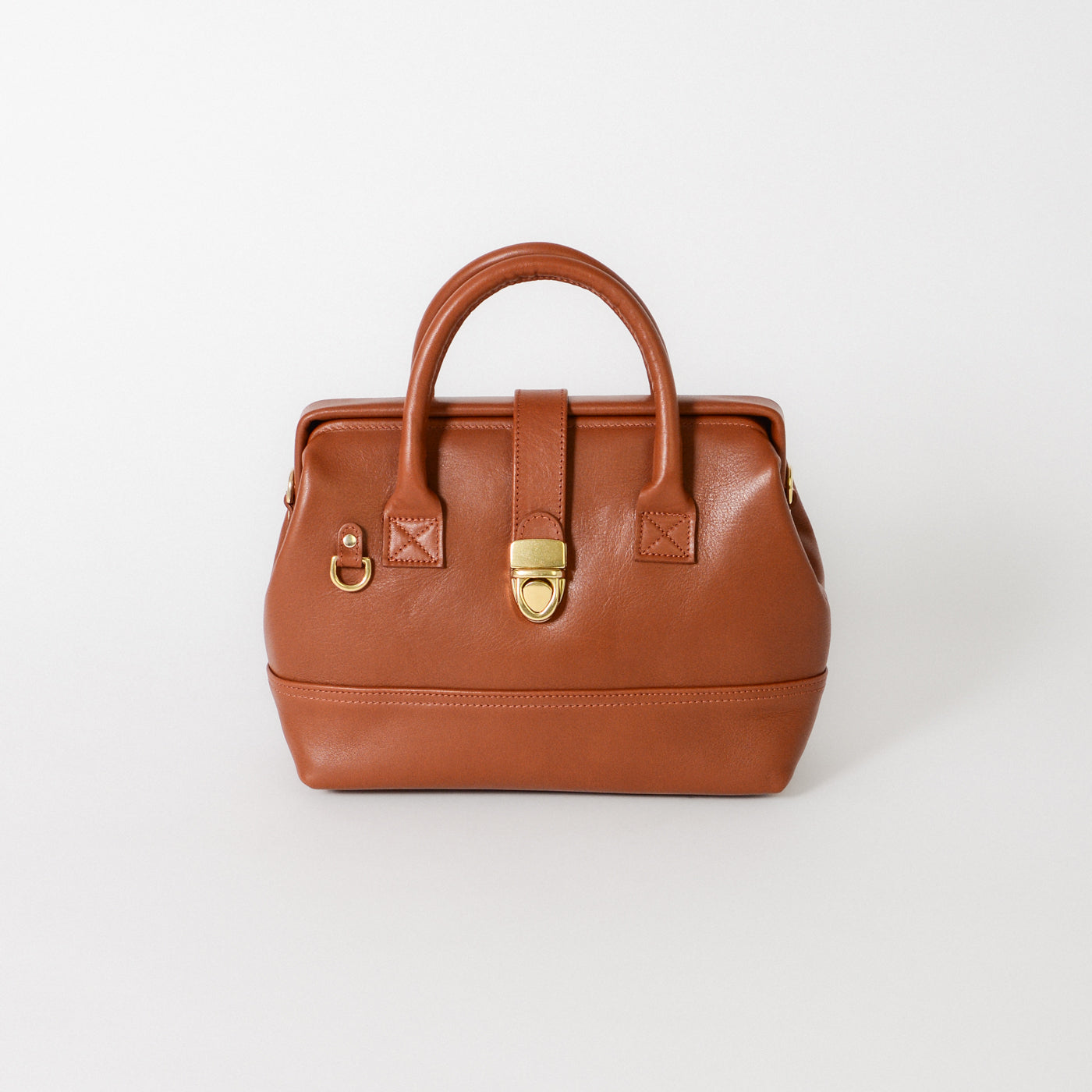 Front view of the Doctor Bag Petite in cognac leather, featuring structured top handles, a signature gold lock closure, and a clean, architectural silhouette.