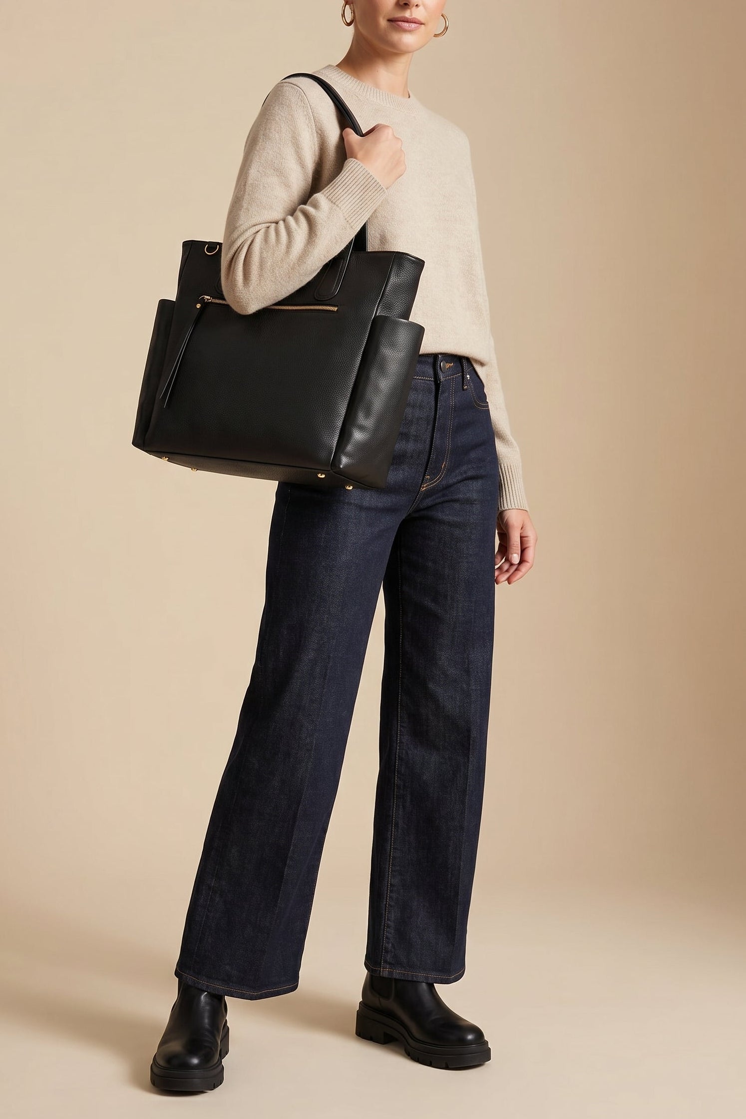 Model carrying the black leather Emily Tote over the shoulder, styled with a neutral sweater, dark denim, and boots—ideal for work and travel.