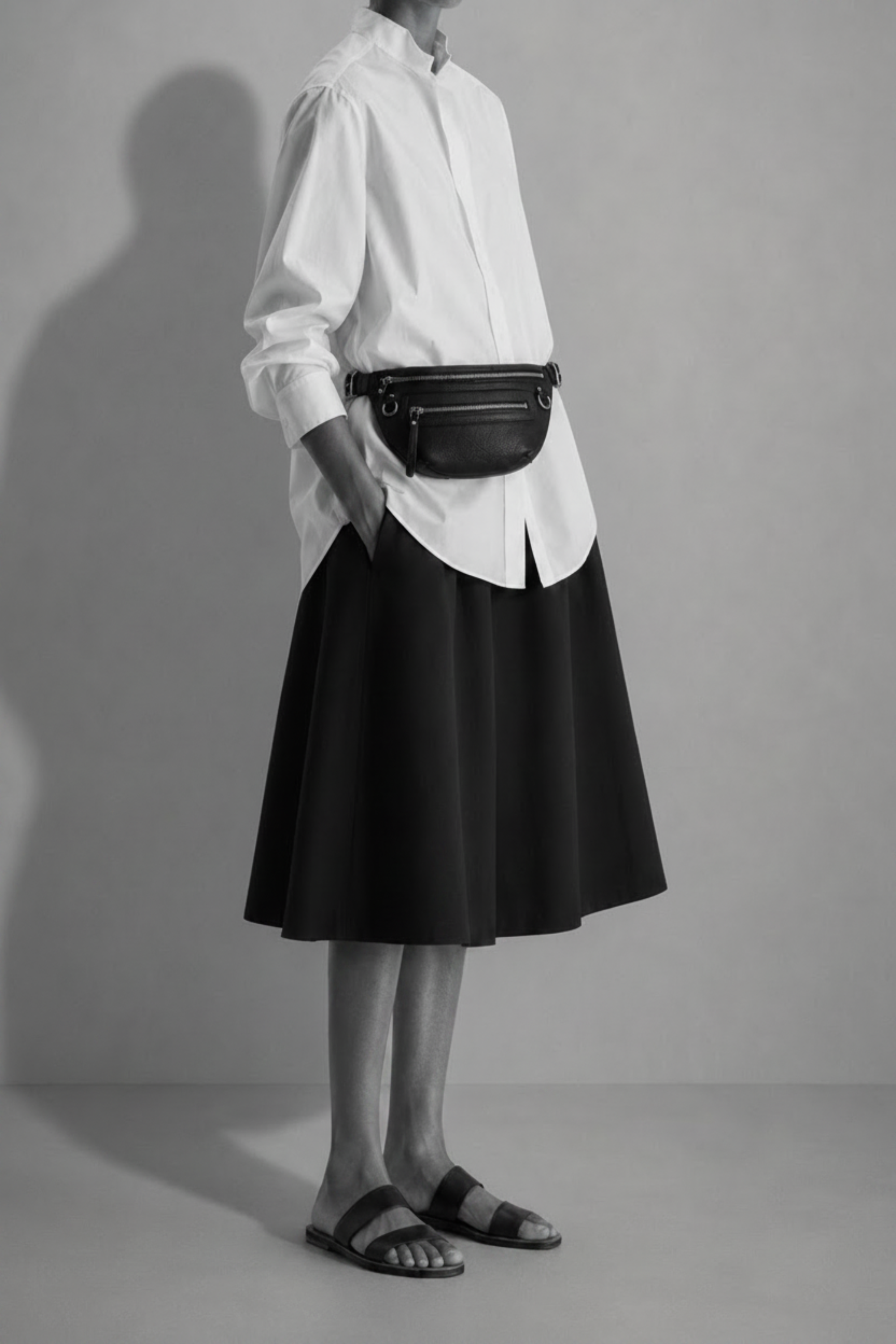 TAH Nomad black leather fanny pack worn at the waist with a white blouse and black skirt