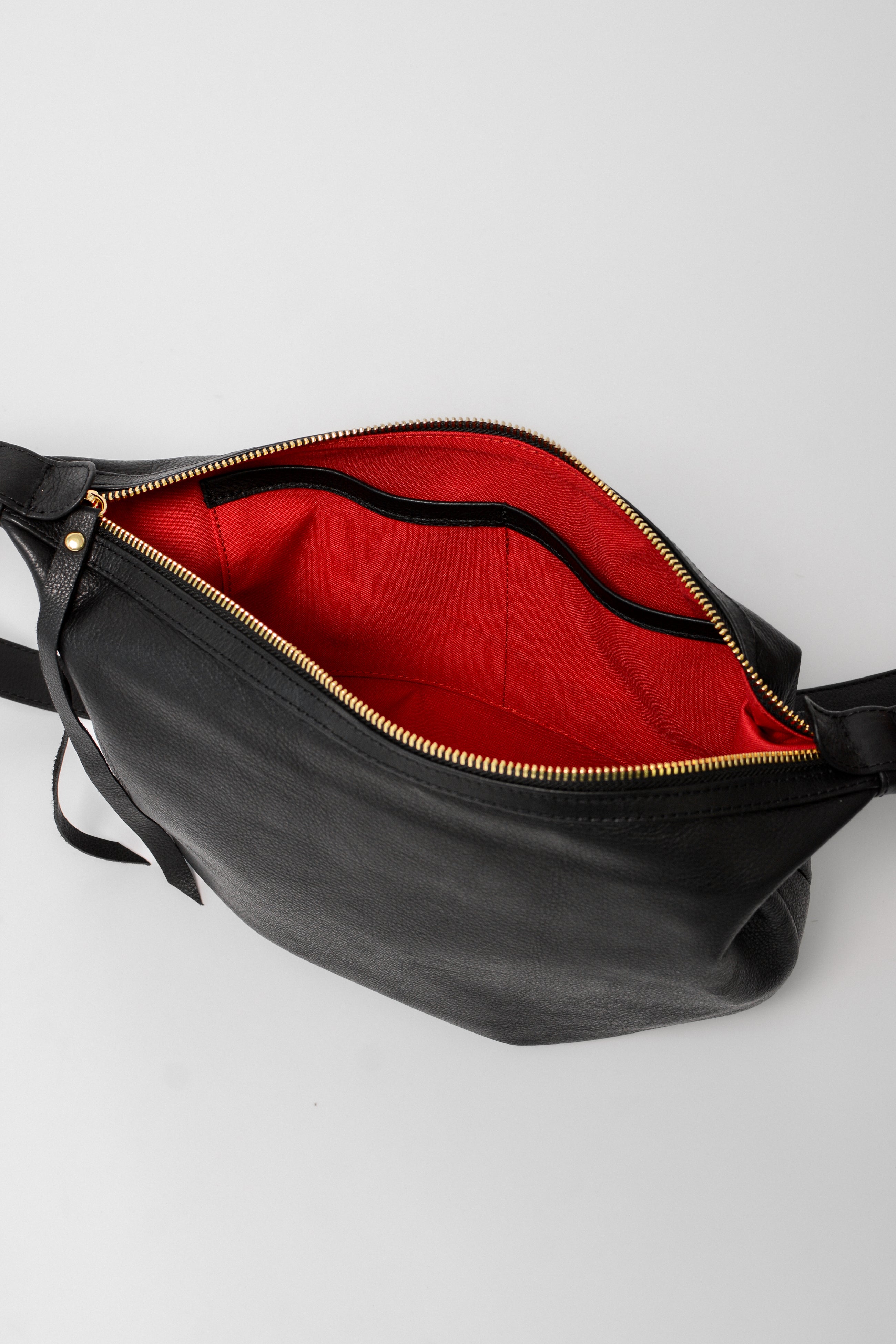 Interior of the black leather Nova Sling Bag showing red lining with slip pockets for easy organization of everyday essentials.