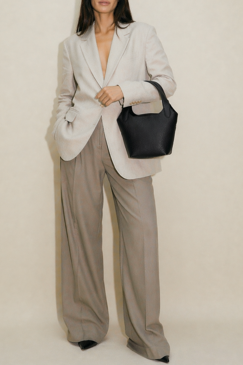 Black leather Phoebe bucket bag carried on arm by model, featuring a structured silhouette, top handle, and minimalist design for an elevated everyday look.