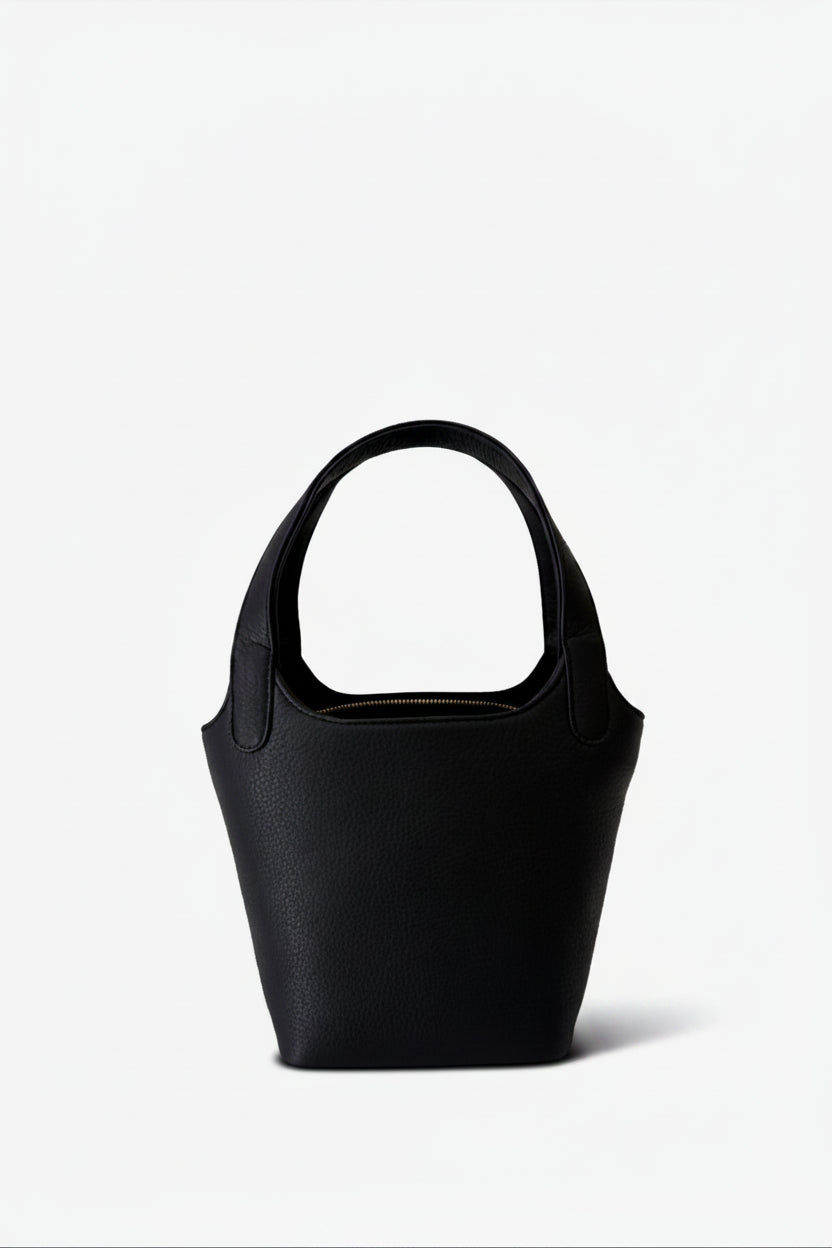 Black leather Phoebe bucket bag with structured silhouette and top handle, featuring a clean, minimalist design for everyday carry.