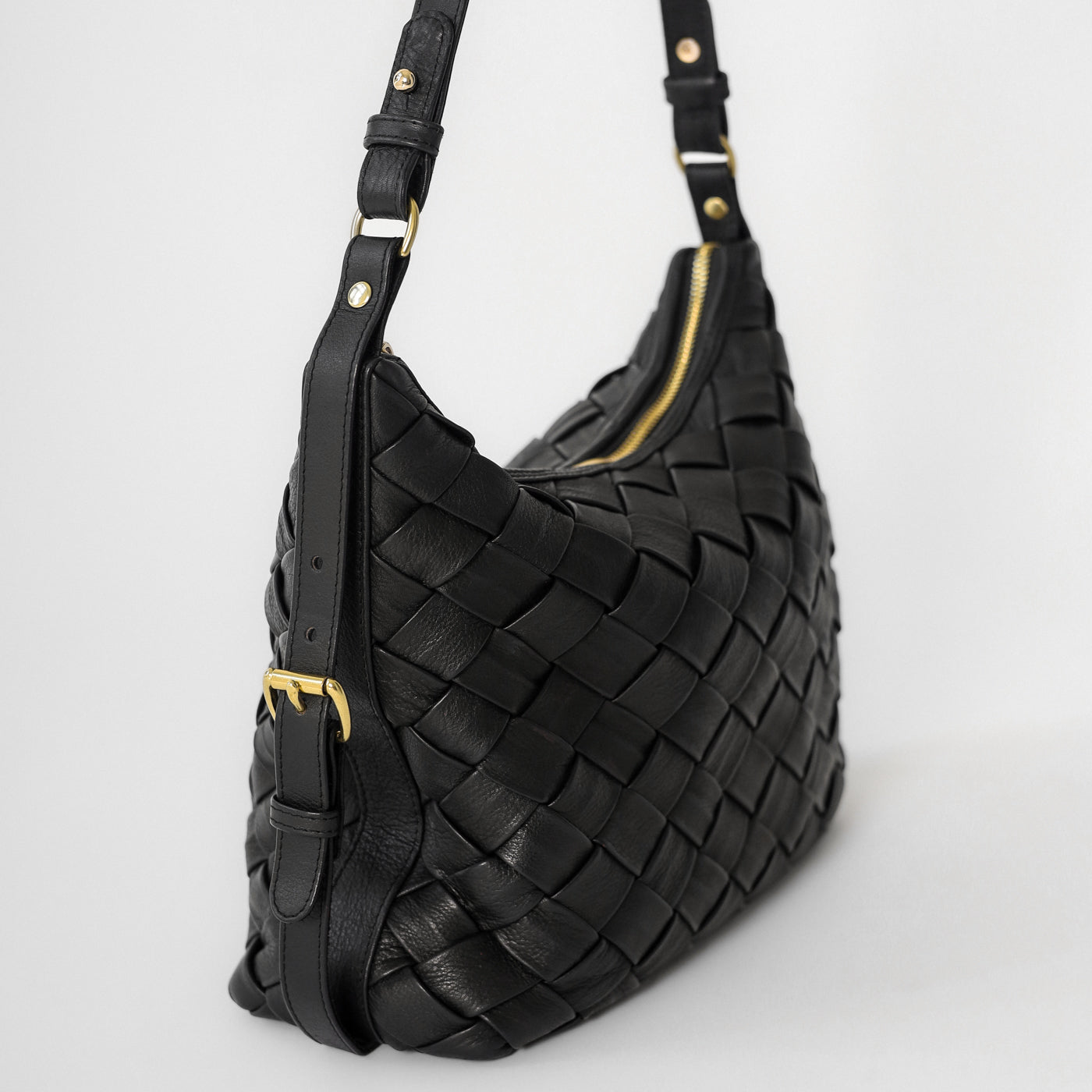 Close-up of the Selena Handwoven black leather bag highlighting the woven craftsmanship, adjustable strap, and gold hardware detailing.