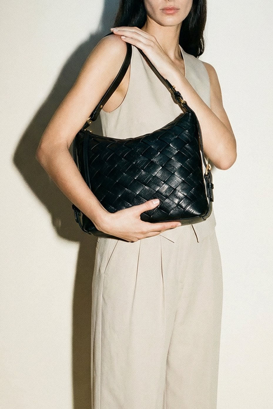 Model wearing the black Selena Handwoven leather bag with intricate woven detailing, styled as a shoulder bag with a relaxed, refined silhouette.