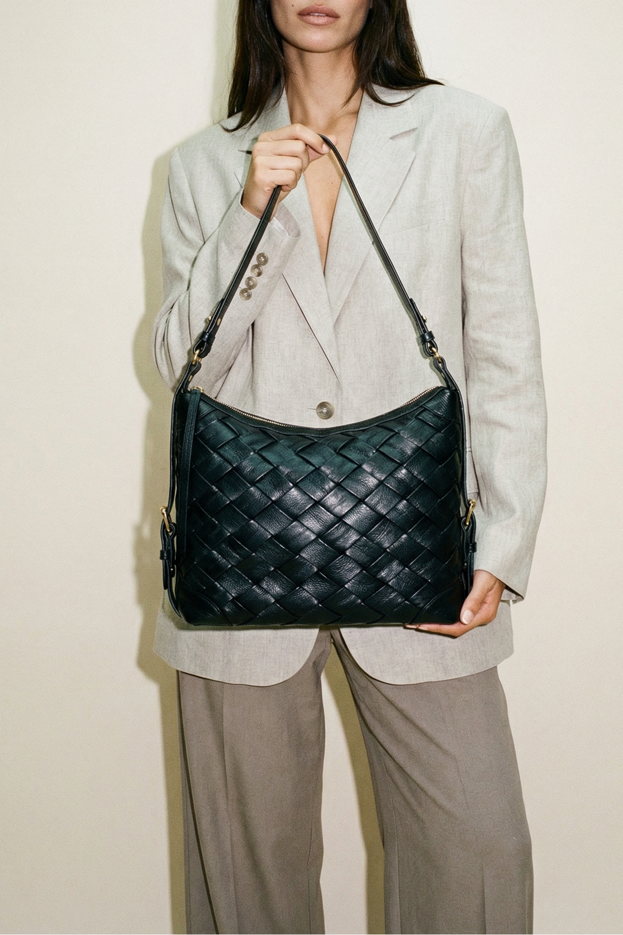 Model wearing the black Selena Handwoven leather shoulder bag with woven texture, styled with a tailored blazer for a polished, modern look.